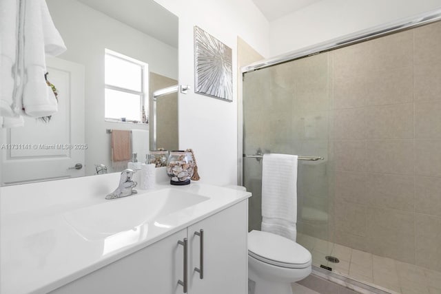 bathroom featuring a shower with door, vanity, and toilet