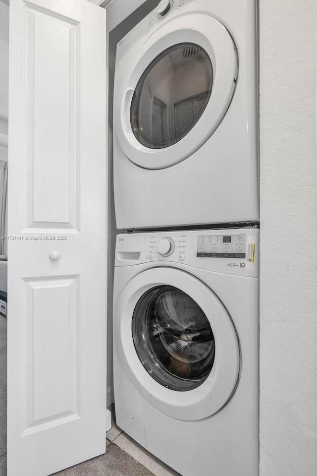 washroom featuring stacked washer and clothes dryer