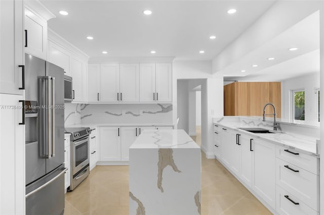 kitchen featuring white cabinetry, stainless steel appliances, light stone countertops, and sink