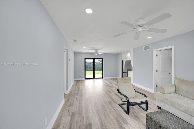 living room with visible vents, baseboards, ceiling fan, and light wood-type flooring