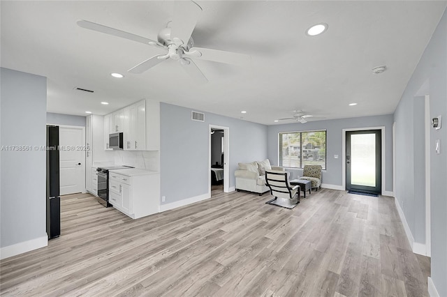 interior space featuring baseboards, ceiling fan, light wood-type flooring, and visible vents