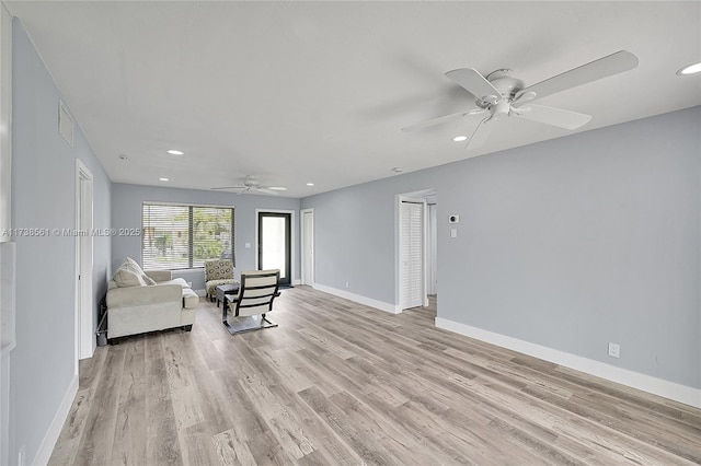 living area with light wood-style floors, baseboards, and ceiling fan