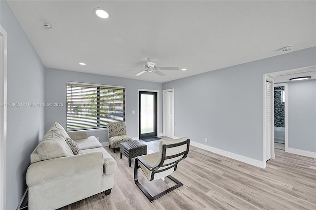 living room with light hardwood / wood-style flooring and ceiling fan