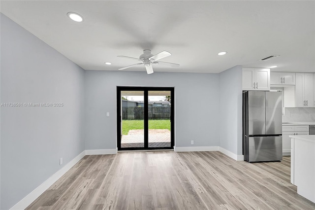 kitchen with stainless steel refrigerator, white cabinetry, ceiling fan, and light hardwood / wood-style flooring