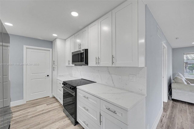 kitchen with white cabinetry, backsplash, black range with electric stovetop, light stone countertops, and light hardwood / wood-style flooring