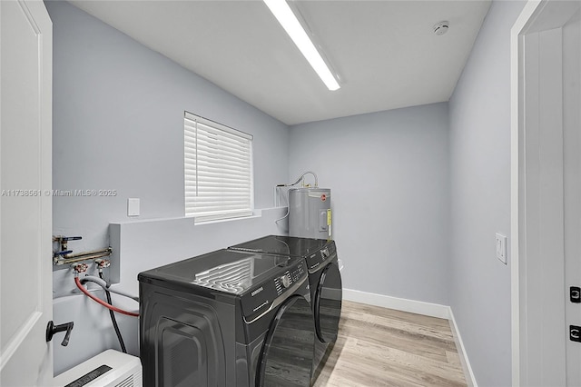 laundry room featuring washing machine and clothes dryer, light hardwood / wood-style floors, and water heater