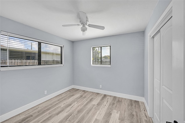 unfurnished bedroom featuring baseboards, ceiling fan, light wood finished floors, and a closet