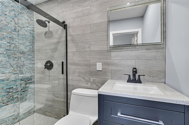 bathroom featuring toilet, a shower with shower door, tile walls, vanity, and backsplash