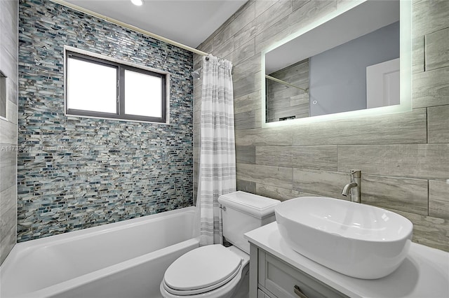 full bath featuring tile walls, shower / bath combo with shower curtain, vanity, and toilet