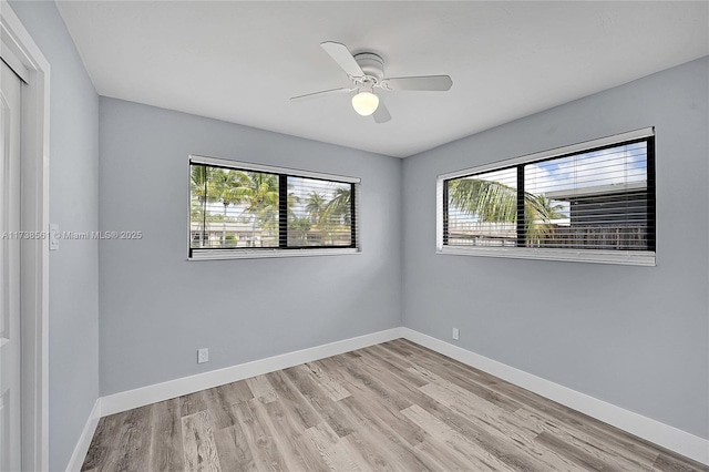 spare room with light wood-type flooring, a ceiling fan, baseboards, and a wealth of natural light