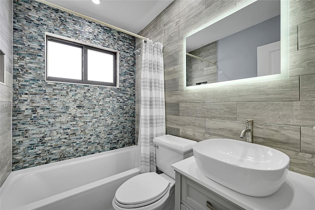 full bathroom with tile walls, vanity, toilet, and shower / bath combo with shower curtain