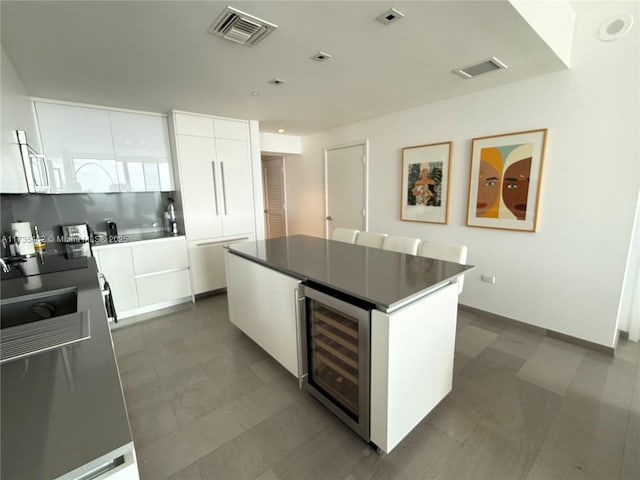 kitchen featuring white cabinetry, beverage cooler, and a kitchen island