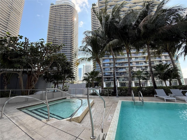 view of swimming pool featuring a hot tub and a patio