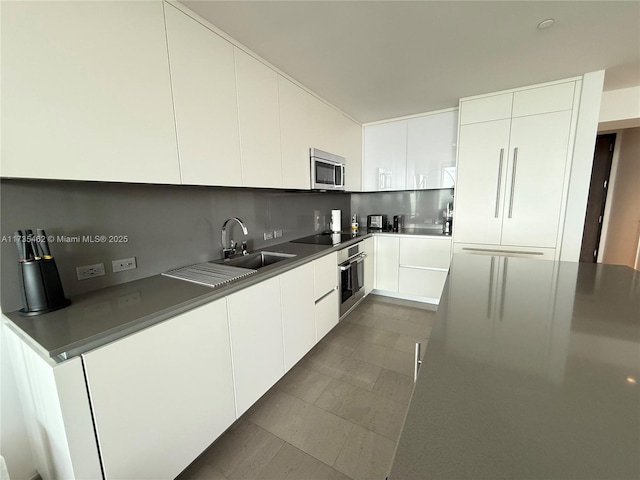 kitchen with white cabinetry, backsplash, stainless steel appliances, and sink