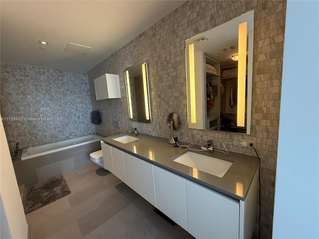 bathroom with toilet, tasteful backsplash, tile walls, vanity, and a bathtub