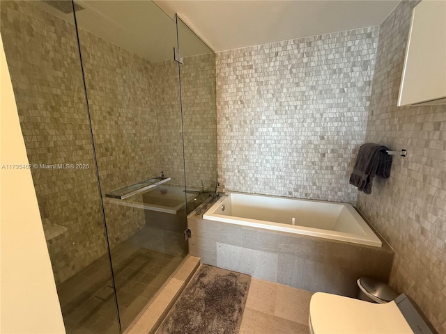 bathroom featuring tile walls, independent shower and bath, and toilet