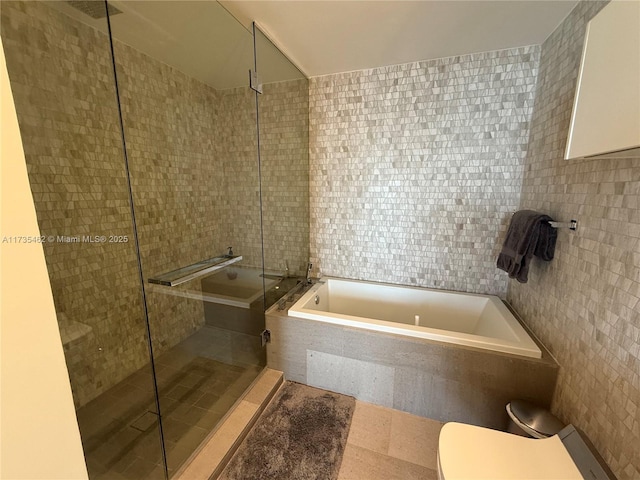 bathroom with tile walls, plus walk in shower, and toilet