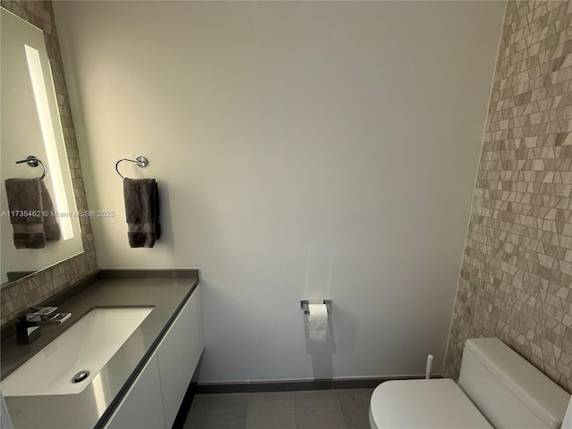 bathroom featuring vanity, tile walls, and toilet