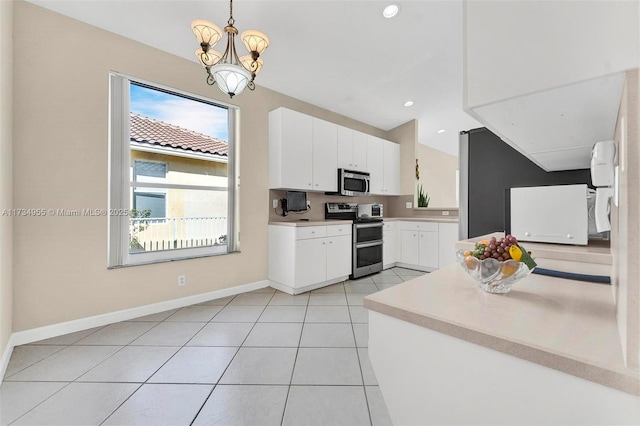 kitchen with light tile patterned flooring, appliances with stainless steel finishes, white cabinetry, a chandelier, and hanging light fixtures