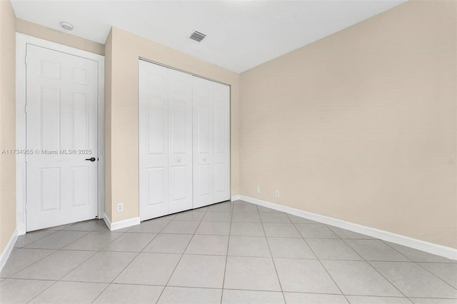 unfurnished bedroom with lofted ceiling, light tile patterned floors, and a closet