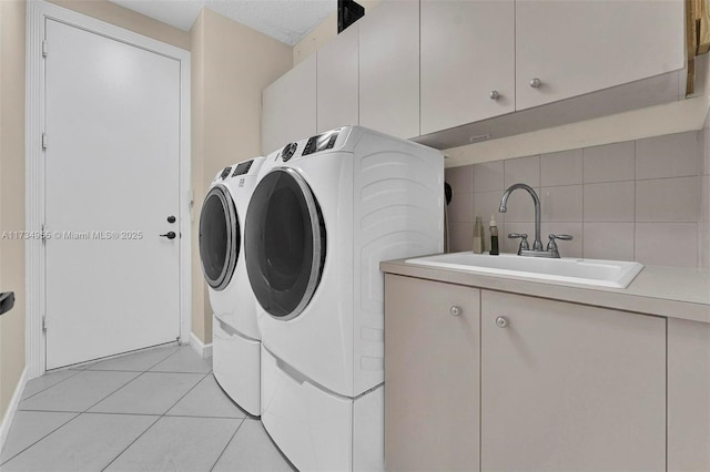 clothes washing area featuring cabinets, washing machine and dryer, sink, and light tile patterned floors