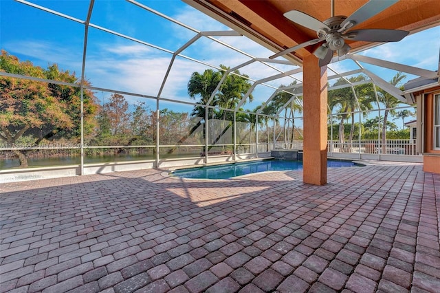 view of pool with a water view, ceiling fan, a patio area, and glass enclosure