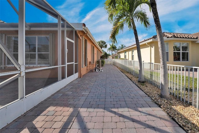 view of home's exterior with a patio area and glass enclosure