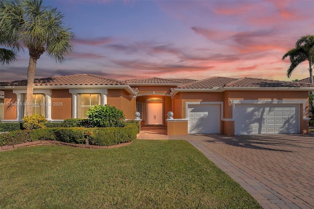 mediterranean / spanish-style house featuring a garage and a lawn