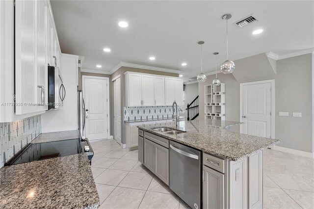 kitchen featuring sink, white cabinetry, hanging light fixtures, stainless steel appliances, and a center island with sink