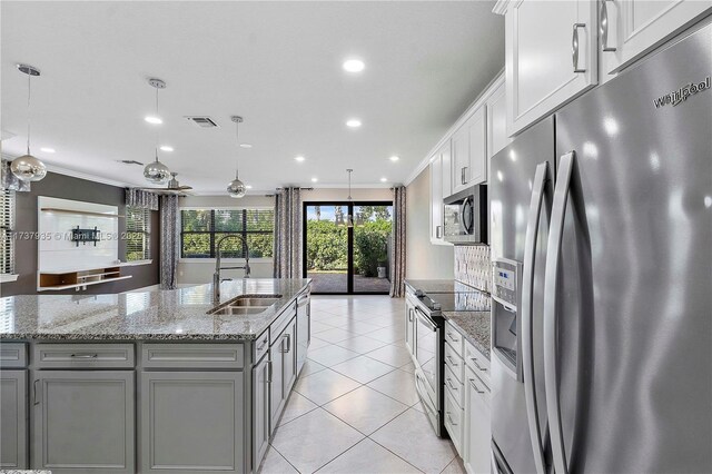 kitchen featuring pendant lighting, sink, white cabinets, stainless steel appliances, and a center island with sink