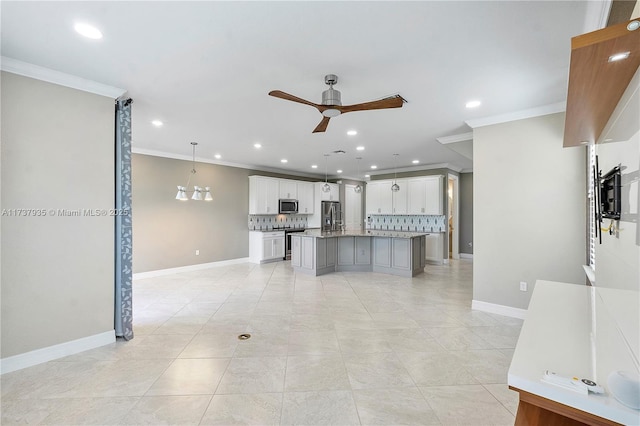 kitchen featuring appliances with stainless steel finishes, hanging light fixtures, a center island, tasteful backsplash, and white cabinets