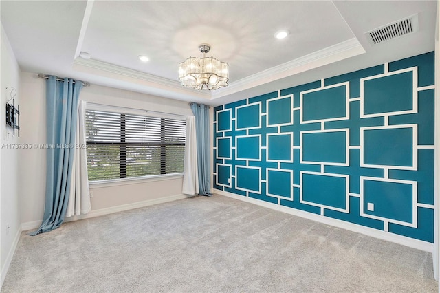 spare room featuring ornamental molding, carpet floors, an inviting chandelier, and a tray ceiling