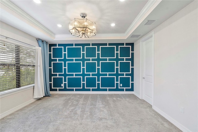 empty room featuring an inviting chandelier, ornamental molding, a tray ceiling, and carpet floors