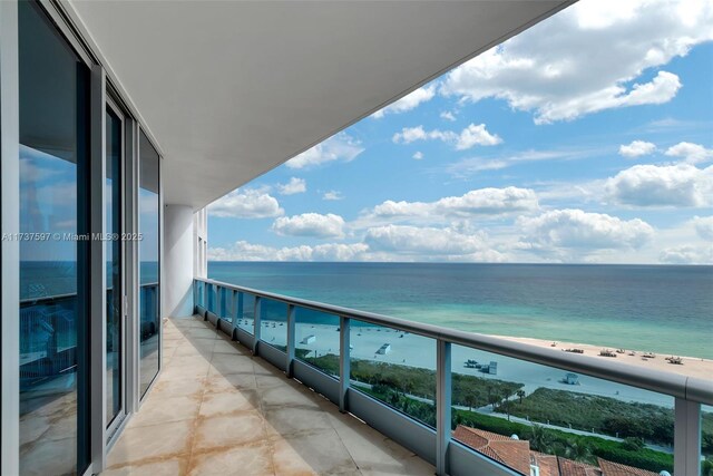 balcony featuring a water view and a beach view