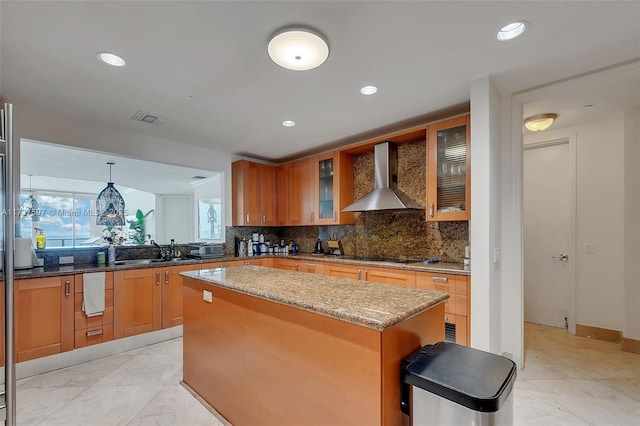 kitchen featuring wall chimney exhaust hood, sink, black electric cooktop, a kitchen island, and pendant lighting