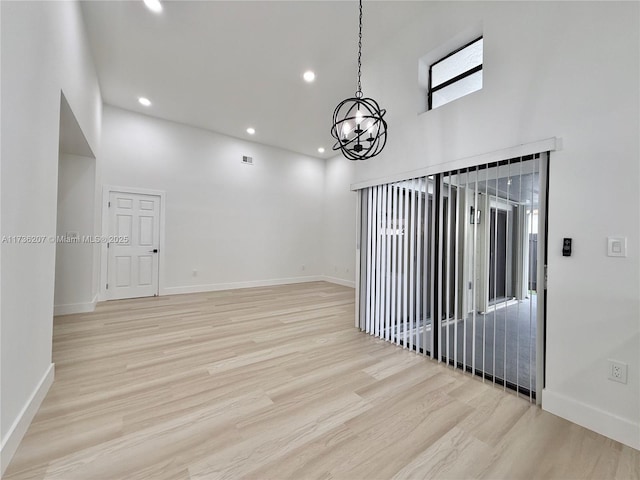 unfurnished room with a towering ceiling and light wood-type flooring