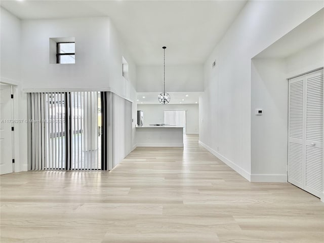 hallway featuring a high ceiling, a wealth of natural light, and light wood-type flooring