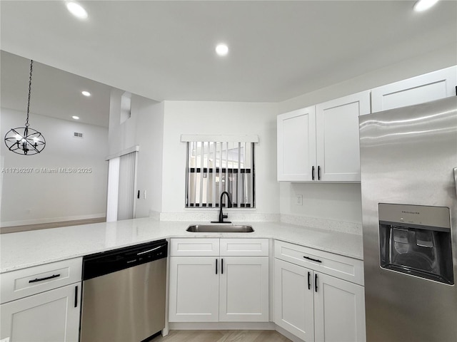 kitchen with pendant lighting, sink, white cabinets, kitchen peninsula, and stainless steel appliances