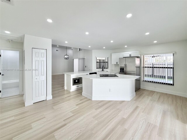 kitchen featuring a kitchen island, decorative light fixtures, built in microwave, white cabinetry, and stainless steel refrigerator with ice dispenser