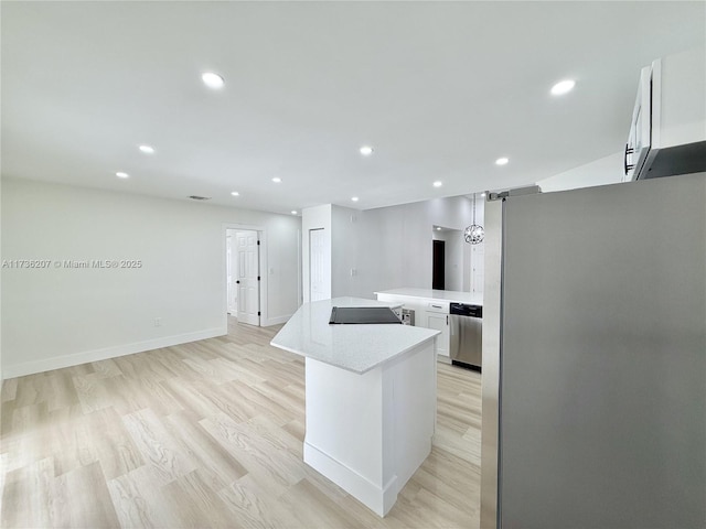 kitchen with white cabinetry, appliances with stainless steel finishes, a center island, and light hardwood / wood-style floors