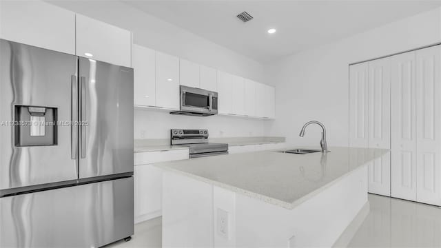 kitchen with appliances with stainless steel finishes, sink, a kitchen island with sink, and white cabinets