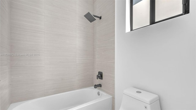 bathroom featuring tiled shower / bath combo and toilet