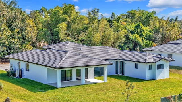 rear view of house with cooling unit, a lawn, and a patio area