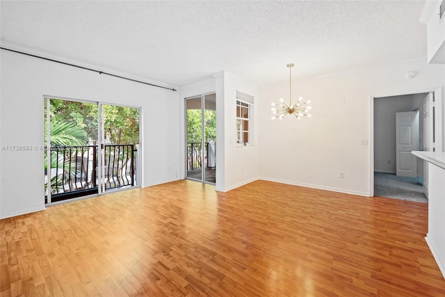 unfurnished room featuring a textured ceiling, light hardwood / wood-style floors, and a chandelier