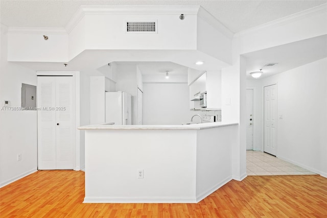 kitchen featuring white refrigerator, crown molding, light hardwood / wood-style flooring, and white cabinets