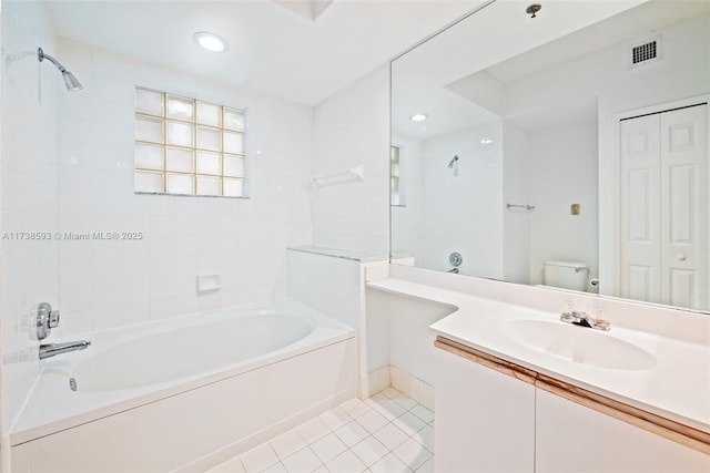 full bathroom featuring tile patterned flooring, vanity, tiled shower / bath combo, and toilet