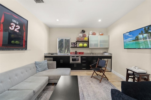 living room featuring wet bar and light wood-type flooring