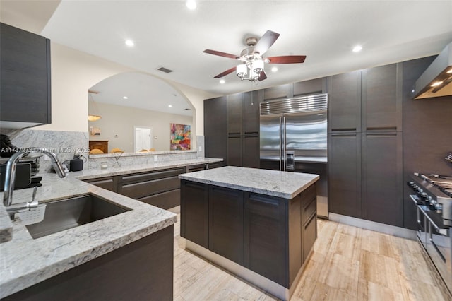 kitchen with kitchen peninsula, sink, light stone countertops, and premium appliances