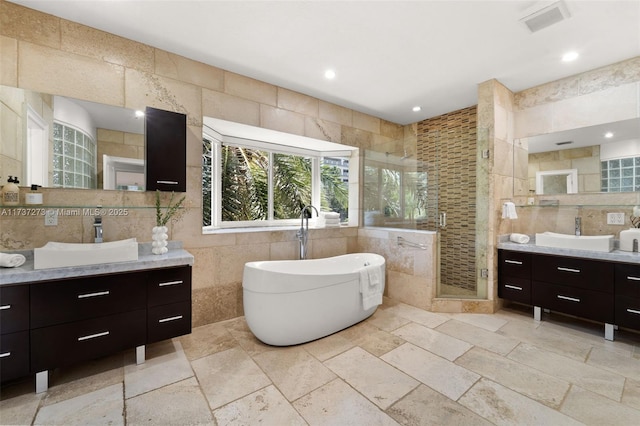 bathroom featuring shower with separate bathtub, tile walls, and vanity