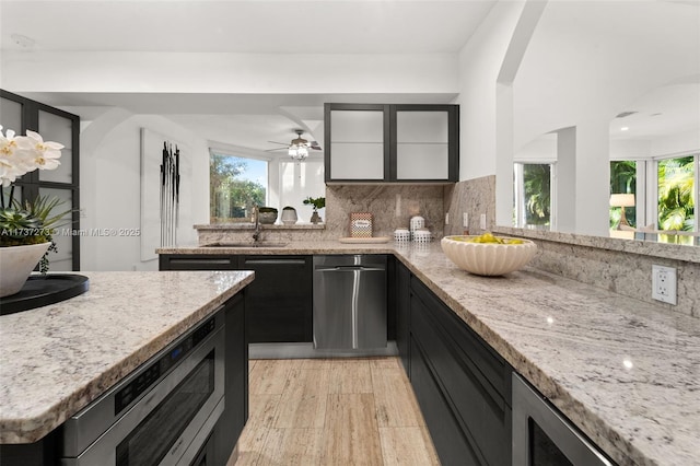 kitchen featuring light stone countertops, sink, backsplash, and appliances with stainless steel finishes